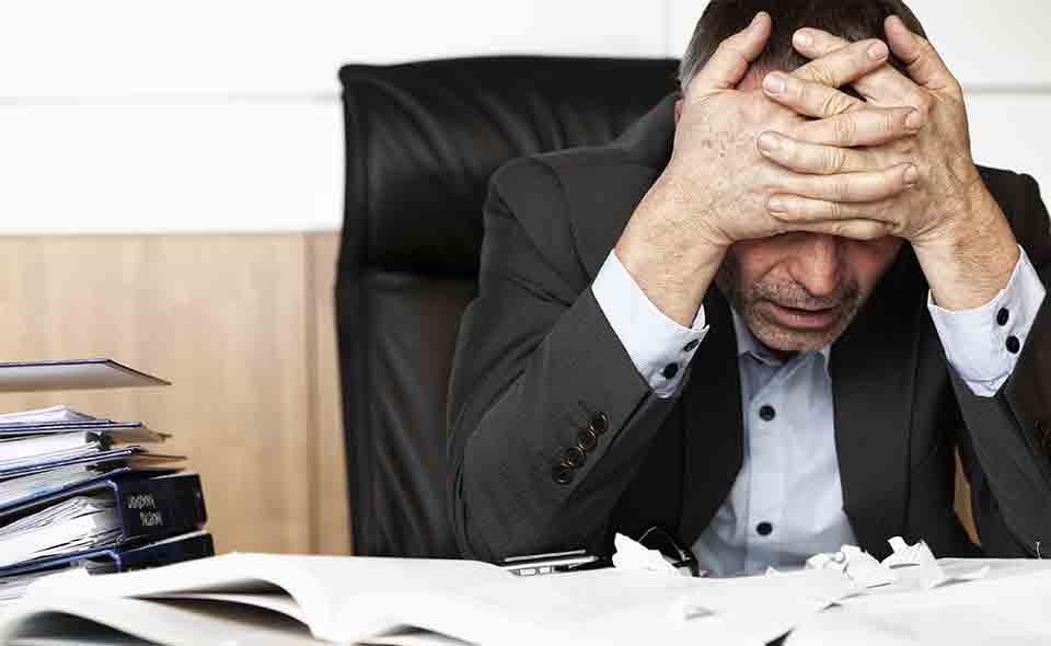 A picture of a stressed out male worker at his desk.